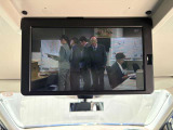 【純正後席フリップダウンモニター】天井から迫力の大画面。後部座席のお子様やご家族へ映画やアニメを届けます。長距離ドライブの退屈を和らげ、移動時間を楽しい思い出に変えます。