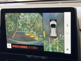 画面には後方の映像と車両周辺の表示が並び、ガイド線も確認できます。駐車時に後方や周囲の位置関係を把握しやすく、日常の車庫入れをサポートします。