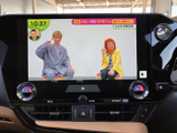 画面にテレビ番組が表示され、停車中の休憩時間などに映像を楽しめます。大きく見やすい画面で、空調の操作表示も近くにまとまり、車内で使いやすい構成です。