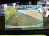 モニターには車両後方の映像と進路の目安が表示され、駐車時の周囲確認をサポートします。画面上で位置関係を把握しやすく、日常の駐車場でも便利にお使いいただけます。