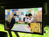 後席用のモニターを備え、停車中に映像を楽しめる装備です。画面に番組映像が表示されており、車内で過ごす時間を活用できます。ご利用の際は、停車した状態でお楽しみください。