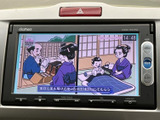 画面には映像コンテンツが表示され、停車中の待ち時間などに活用できる装備です。画面脇にメニューや現在地、オーディオのボタンがまとまり、必要な操作を探しやすい配置です。