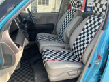 前席は運転席と助手席が並び、前方や窓越しの周囲を確認しやすい室内です。チェック柄のシートカバーと落ち着いた色の内装が、印象的なコントラストを生みます。