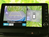 車両後方の映像と周囲を俯瞰した表示を切り替えて確認でき、駐車時の周辺確認をサポートします。画面内の目安線も見ながら位置を把握しやすく、狭い場所での駐車や切り返しに役立ちます。