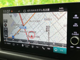 画面には周辺地図が表示され、道路や現在地を見ながら目的地までの経路を確認できます。画面下部のメニューからナビやオーディオなども選べて便利です。